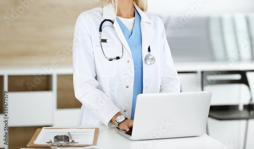 Unknown female physician using laptop computer, close-up. Woman-doctor at work in clinic. Medicine concept