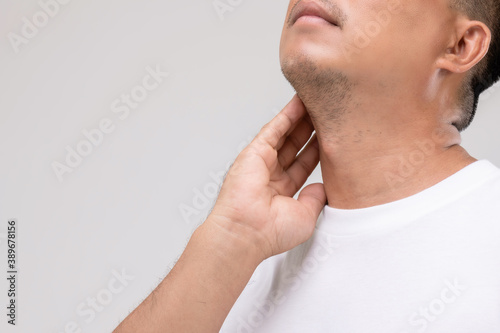 Lymphoma in men concept : Portrait Asian man is touching on his neck at lymph node position. Studio shot isolated on grey photo