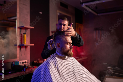 haircut at the hairdresser, in salon. barber male cuts the hair on the handsome young client's head, the process of creating hairstyles for men by professional