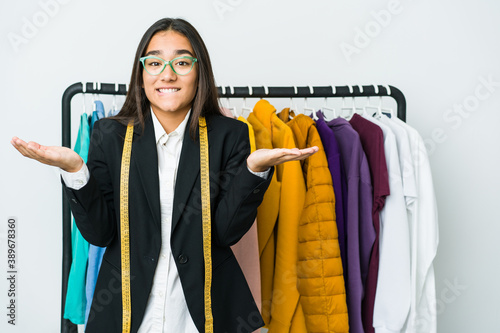 Young asian designer woman isolated on white background confused and doubtful shrugging shoulders to hold a copy space.