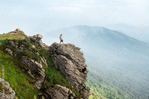 Man standing on top of rocky mountains with cloudy weather