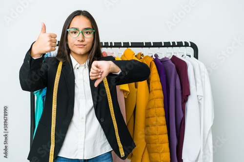 Young asian designer woman isolated on white background showing thumbs up and thumbs down, difficult choose concept