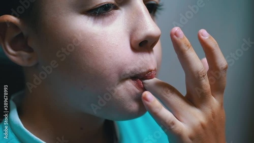Portrait of Boy Who Licks Dirty Fingers and Lips with Tongue after a Tasty Meal photo