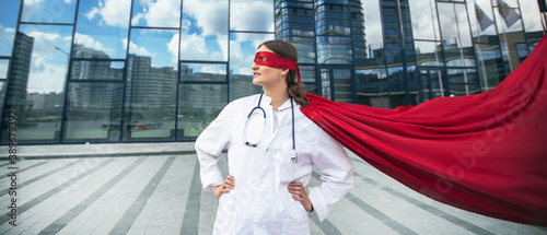 Obraz na płótnie female doctor in a superhero raincoat looks at a city street . w salonie