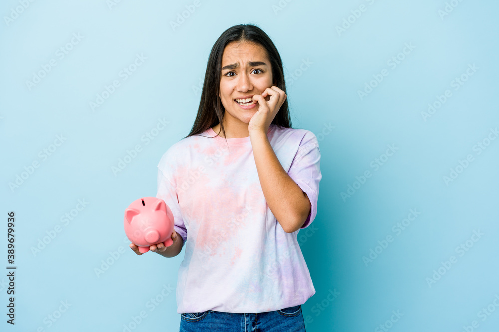 Young asian woman holding a pink bank over isolated background biting fingernails, nervous and very anxious. Young asian woman holding a pink bank over isolated background biting fingernails, nervous and very anxious.
