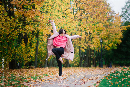 Ballerina dancing in nature among autumn leaves.