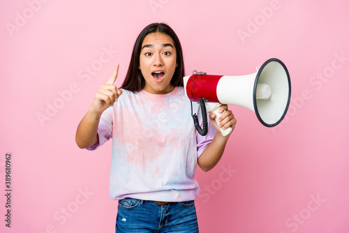 Young asian woman holding a megaphone isolated on pink background having an idea, inspiration concept.