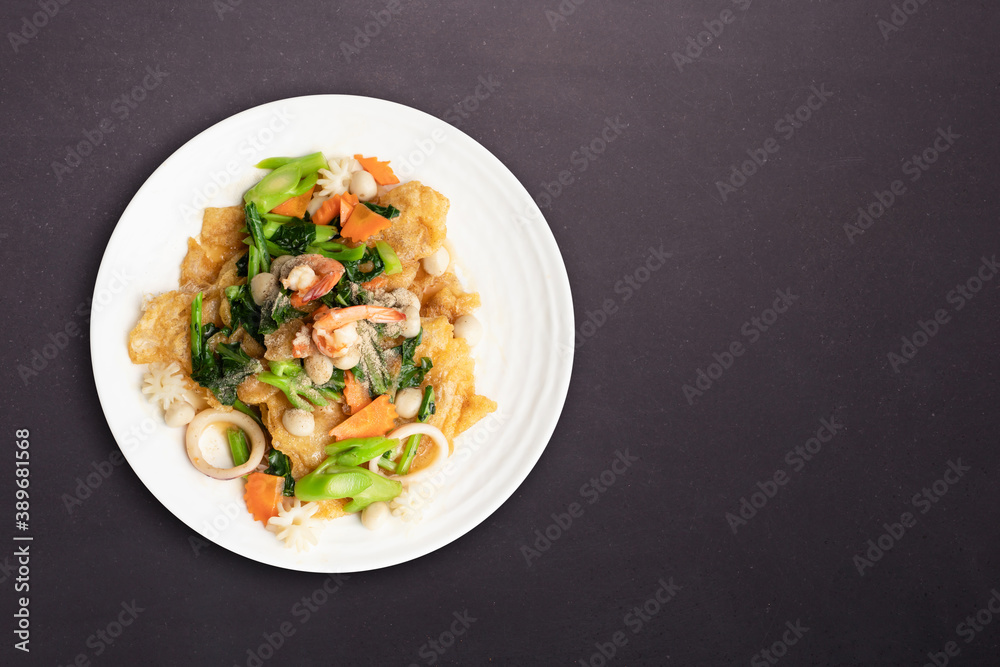 Fried noodle with seafood and vegetable in round white dish isolated on white background. Thai Food concept