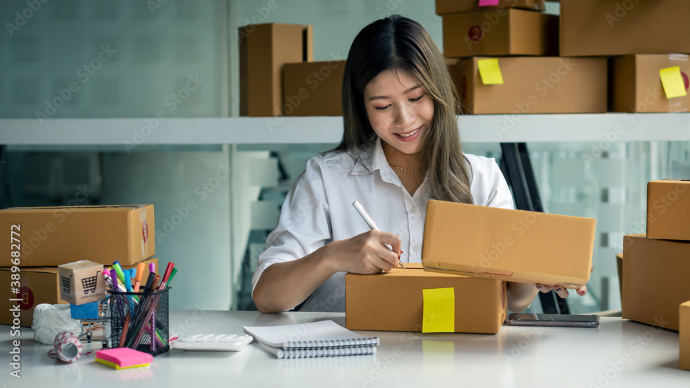 A young woman selling things online starts a small business in a cardboard box at work. Seller provides shipping boxes for online sales customers. A young woman selling things online starts a small business in a cardboard box at work. Seller provides shipping boxes for online sales customers.