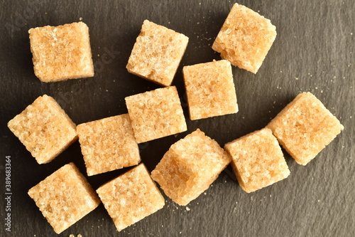 Several cubes of brown sugar, close-up, on a slate board.