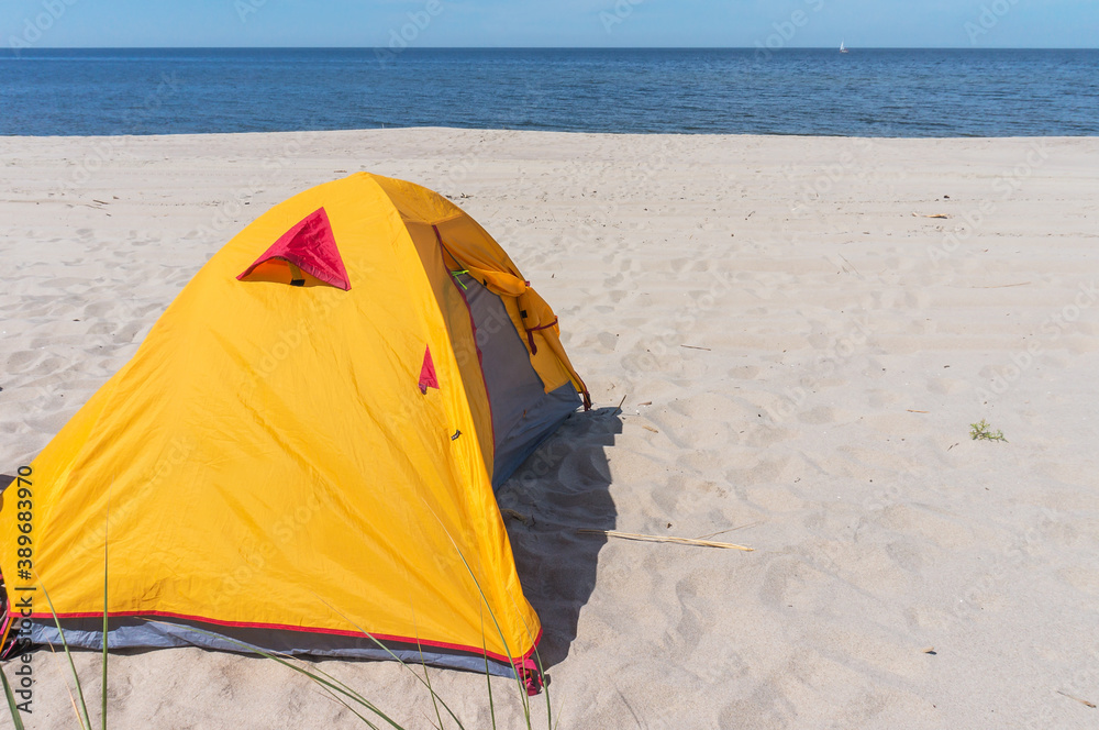 Tent on the beach. Yellow tent on the sea sand.