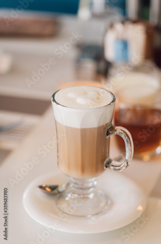 A Glass of hot cappuccino coffee on the table in cafe shop with breakfast background. vintage film color tone.
