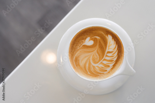 Top view of hot coffee with latte art in a white cup and saucer on white table background in the cafe.