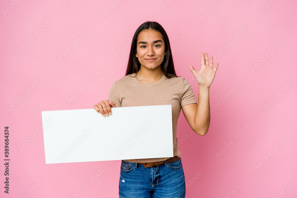 Young asian woman holding a blank paper for white something over isolated background smiling cheerful showing number five with fingers. Young asian woman holding a blank paper for white something over isolated background smiling cheerful showing number five with fingers.