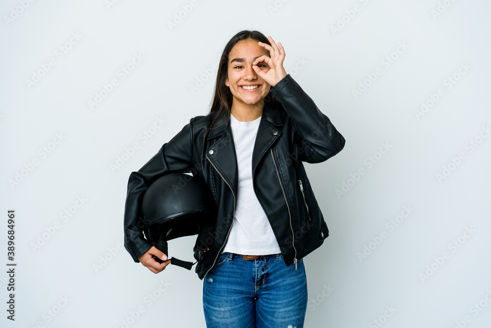 Young asian woman holding a motorbike helmet over isolated background excited keeping ok gesture on eye. Young asian woman holding a motorbike helmet over isolated background excited keeping ok gesture on eye.
