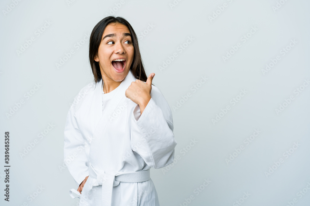 Young asian woman doing karate isolated on white background points with thumb finger away, laughing and carefree. Young asian woman doing karate isolated on white background points with thumb finger away, laughing and carefree.
