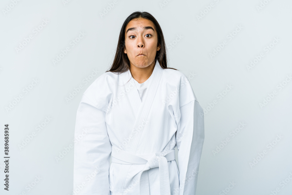 Young asian woman doing karate isolated on white background shrugs shoulders and open eyes confused. Young asian woman doing karate isolated on white background shrugs shoulders and open eyes confused.