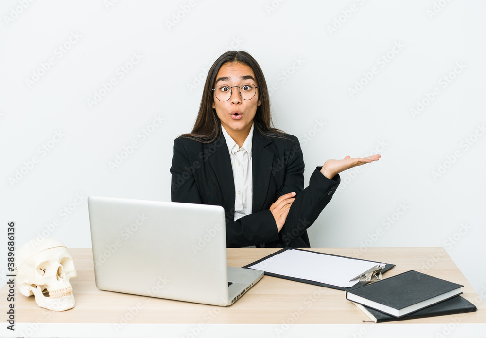 Young traumatologist asian woman isolated on white background impressed holding copy space on palm. Young traumatologist asian woman isolated on white background impressed holding copy space on palm.