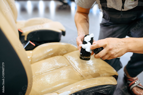 Worker with spray moisturizes car seat, detailing