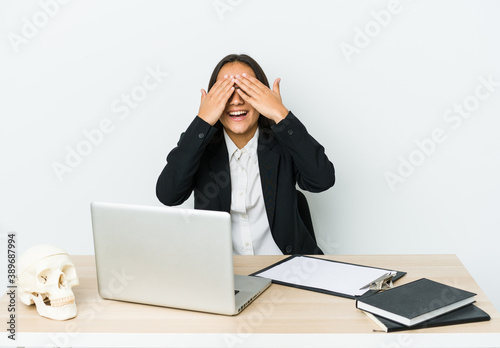 Young traumatologist asian woman isolated on white background covers eyes with hands, smiles broadly waiting for a surprise.