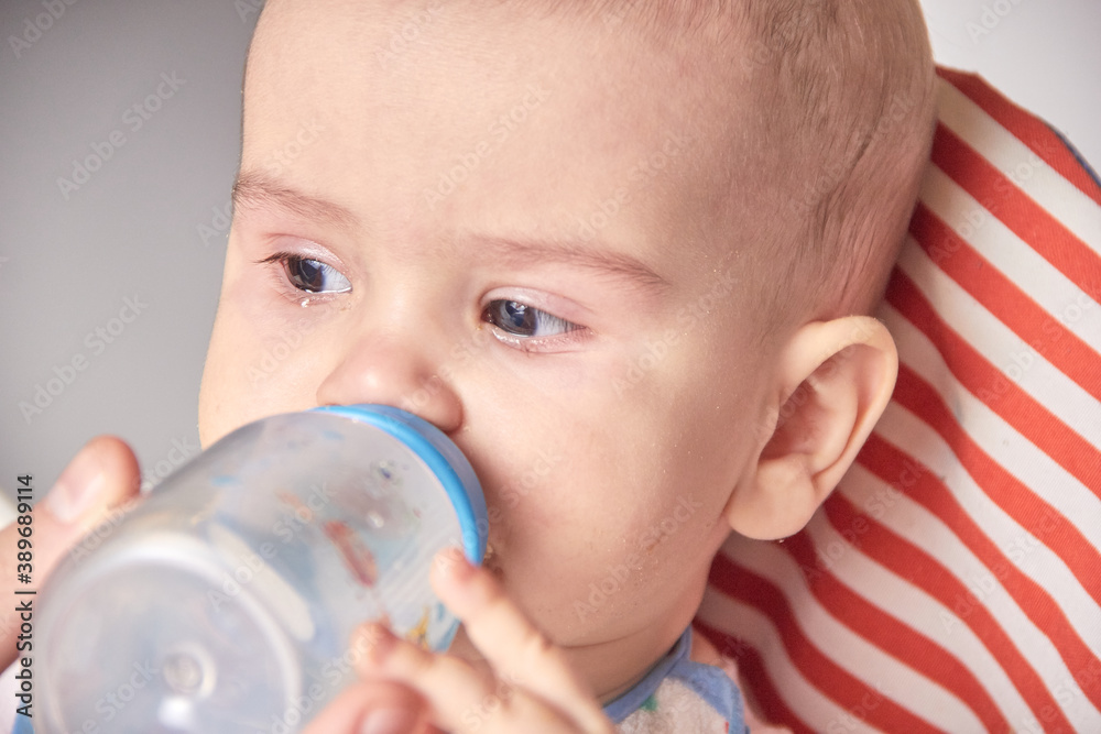 Giving to drink water baby from bottle, closeup Giving to drink water baby from bottle, closeup