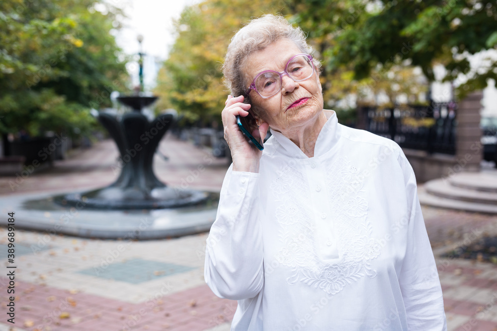 mature european woman talking on the phone in summer park