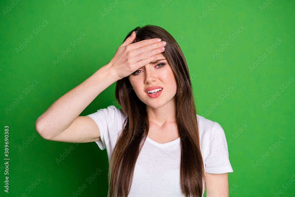 Photo portrait of ill woman touching forehead with one hand isolated on vivid green colored background Photo portrait of ill woman touching forehead with one hand isolated on vivid green colored background