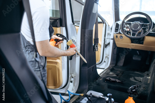 Worker with spray and brush cleans car interior