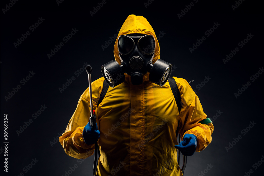 Portrait of a man in a yellow chemical protection suit holding a sprayed disinfectant