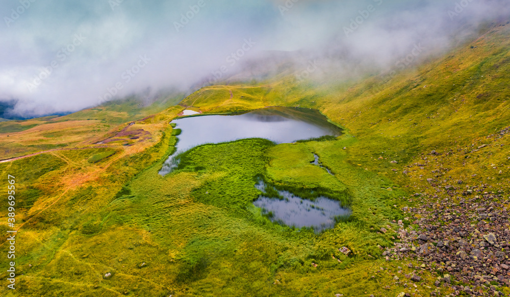 Aerial summer scene of Dohaska lake. Foggy morning view from flying drone of Carpathian mountains, Ukraine, Europe. Beauty of nature concept background...