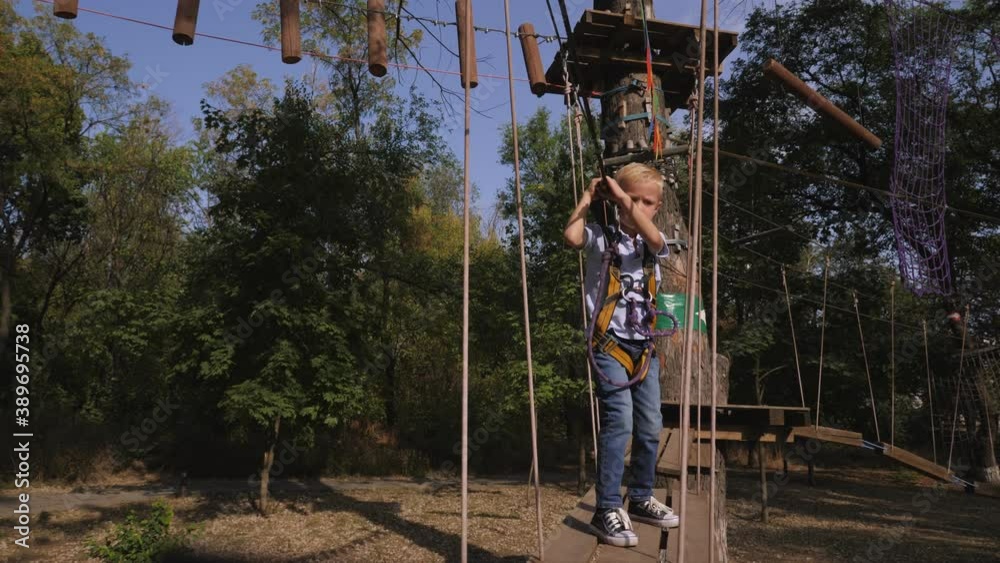Brave little boy is climbing in rope attraction park. Child in a wooden obstacle course in adventure playground. Brave little boy is climbing in rope attraction park. Child in a wooden obstacle course in adventure playground.