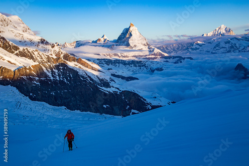 Single mountaineer ski touring with the matterhorn behind photo