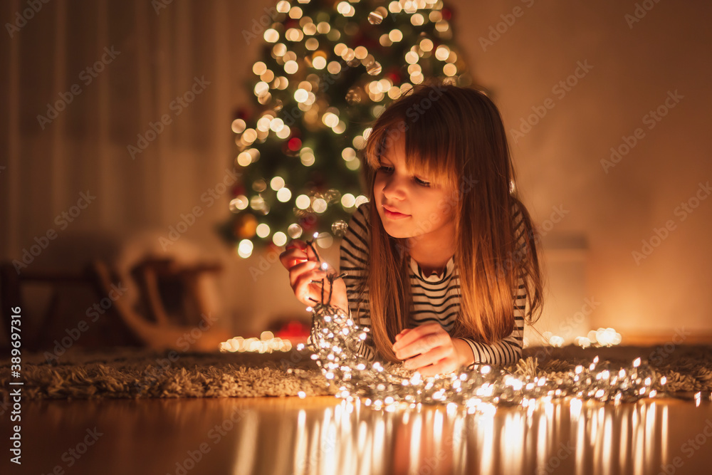 Little girl arranging Christmas lights Stock Photo | Adobe Stock