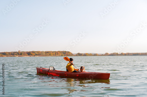 Man with a dog in a canoe on the lake. Young male person with spaniel in a kayak row boat, active free time with pets, companionship, adventure dogs