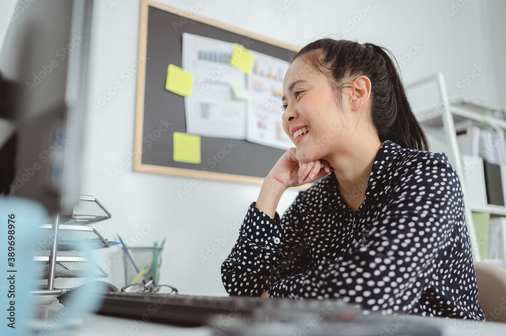 Business woman working and sitting at desk at office,placing chin on her hands and smiling,looking at computer. Business woman and working online concept Business woman working and sitting at desk at office,placing chin on her hands and smiling,looking at computer. Business woman and working online concept