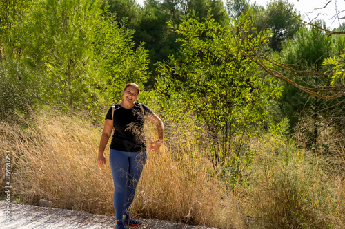 Pretty middle-aged woman dressed in black t-shirt hiking on a nature trail © Andres