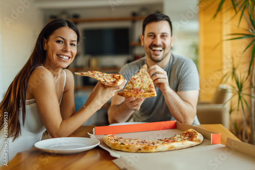 Cute couple eating pizza for breakfast  portrait.