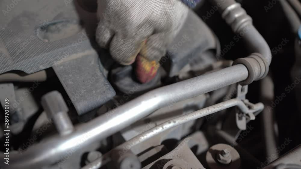 a gloved handyman twists the plug after replacing the engine oil in the