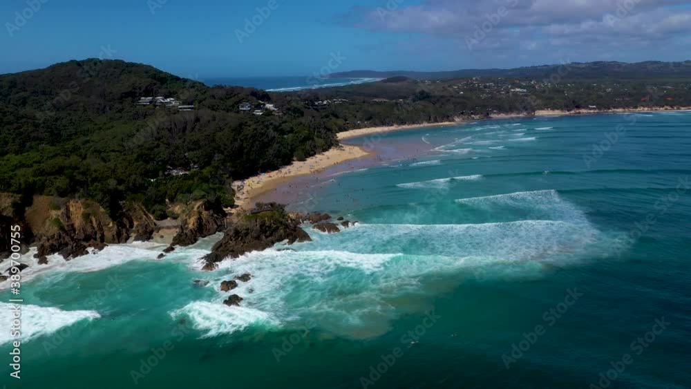 Wide rotating drone shot of surfers in the ocean at Wategos Beach in Byron Bay, Australia Wide rotating drone shot of surfers in the ocean at Wategos Beach in Byron Bay, Australia