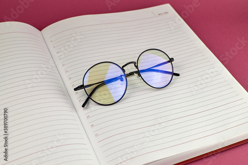 The office concept. Round glasses on an open diary. Fashionable round glasses.