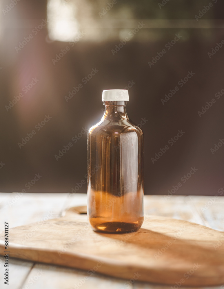 An empty bottle photographed on the wooden tray with dramatic window light & lens flare. An empty bottle photographed on the wooden tray with dramatic window light & lens flare.