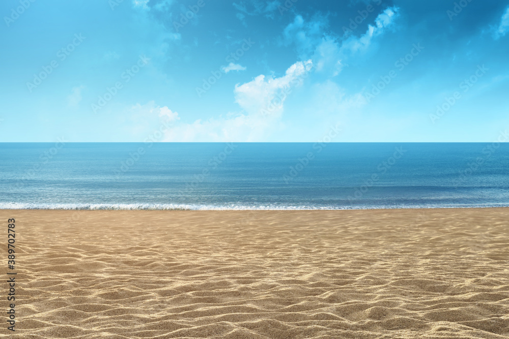 Background of a sandy beach with sea and blue sky on a summer day