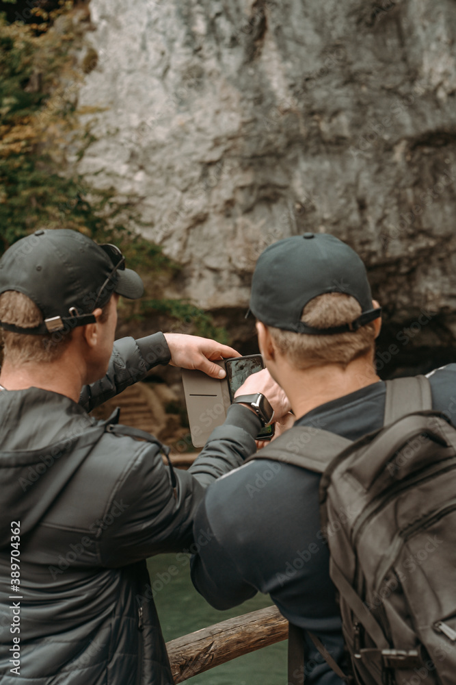 Nice mountain views at Plitvice Lakes Park. Croatia. Two guys tourists take a photo of the cave Nice mountain views at Plitvice Lakes Park. Croatia. Two guys tourists take a photo of the cave