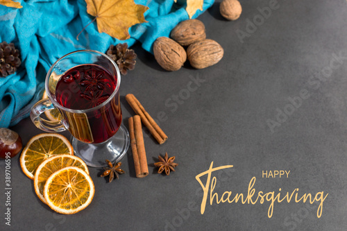 Thanksgiving greetings. Set for mulled wine, wine, spices, leaves, cones, scarf on a gray background, top view. Kaligraphic capital inscription.