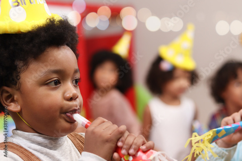 Happy birthday party event, adorable African American boy with curly wearing birthday hat, kids celebrate birthday party together, happy children have fun together