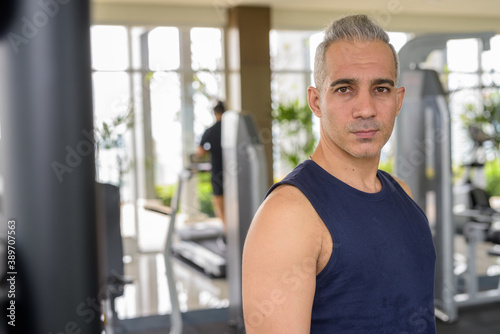 Portrait of mature handsome Persian man at the gym ready to exercise