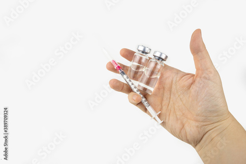 Two vials with medicine and syringe in a hand for injection treatment. Covid-19 vaccine concept. Isolated on white background