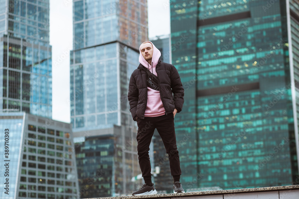 Handsome casual man in black jacket and pink hoody standing on a skyscraper view. Handsome casual man in black jacket and pink hoody standing on a skyscraper view.