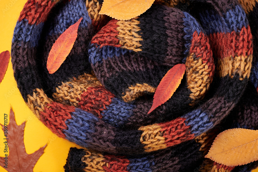 Fototapeta premium Scarf with leaves on yellow background, flat lay photo.