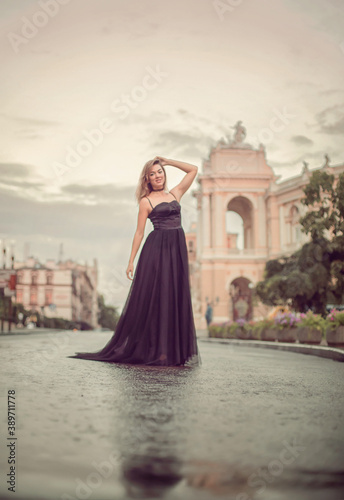 
A girl in a long black dress walks through the old city